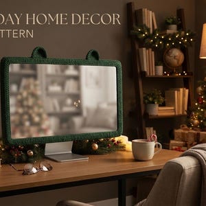 Peut inclure: Une housse de moniteur d'ordinateur en crochet vert foncé avec deux petites oreilles arrondies sur le bord supérieur. Le texte HOLIDAY HOME DECOR PDF PATTERN est affiché dans le coin supérieur gauche, indiquant un modèle numérique pour cet article.