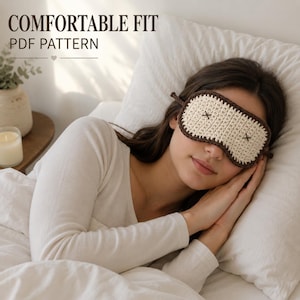 Könnte beinhalten: Eine gehäkelte Schlafmaske mit cremefarbener Mitte und zwei dunkelbraun gestickten X-Formen als Augen, eingefasst von einem dunkelbraunen Garnrand. Der Text COMFORTABLE FIT PDF PATTERN ist in der oberen linken Ecke des Bildes zu sehen.