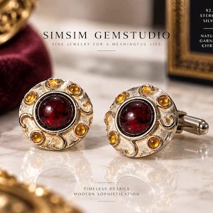Puede incluir: Un par de gemelos redondos de plata de ley con un granate cabujón central rodeado de pequeñas piedras de citrino. La superficie de plata tiene un acabado martillado texturizado con detalles decorativos. Texto: SIMSIM GEMSTUDIO.
