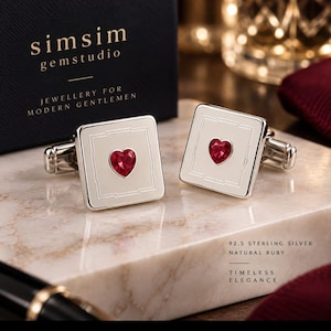 May include: A pair of square silver cufflinks featuring a central heart-shaped red ruby. The cufflinks have a polished finish with an engraved border. Text on the box reads simsim gemstudio JEWELLERY FOR MODERN GENTLEMEN and 92.5 STERLING SILVER.
