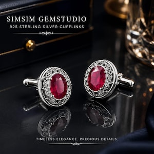 Puede incluir: Un par de gemelos de plata de ley 925 con piedras rojas de corte ovalado rodeadas de intrincados detalles de filigrana de plata. El texto SIMSIM GEMSTUDIO 925 STERLING SILVER CUFFLINKS y TIMELESS ELEGANCE. PRECIOUS DETAILS. es visible.