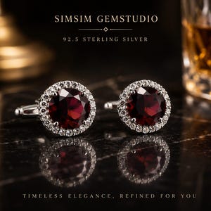 Puede incluir: Un par de gemelos de plata de ley 92.5 con piedras preciosas de granate rojo oscuro redondas rodeadas por un halo de pequeñas piedras blancas transparentes. El texto SIMSIM GEMSTUDIO y 92.5 STERLING SILVER es visible sobre los gemelos.