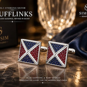 Op de afbeelding: Een paar vierkante manchetknopen van 92.5 sterling zilver met een geometrisch patroon ingelegd met blauwe saffier en robijnstenen. De manchetknopen worden getoond met de tekst CUFFLINKS, 92.5 STERLING SILVER en BLUE SAPPHIRE & RUBY STONES.