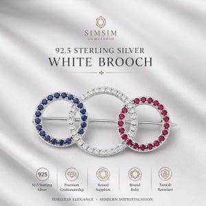 Può includere: Una spilla in argento sterling 92.5 con tre anelli circolari intrecciati. L'anello sinistro è incastonato con zaffiri blu, l'anello centrale con pietre chiare e l'anello destro con rubini rossi. Il testo include SIMSIM GEMSTUDIO e 92.5 STERLING SILVER WHITE BROOCH.
