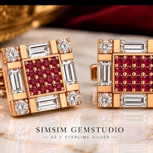 Puede incluir: Un par de gemelos cuadrados hechos de plata de ley 92.5 con acabado dorado. Cada gemelo presenta un grupo cuadrado central de pequeñas piedras rojas, rodeado por cuatro piedras claras de corte baguette y cuatro piedras redondas.