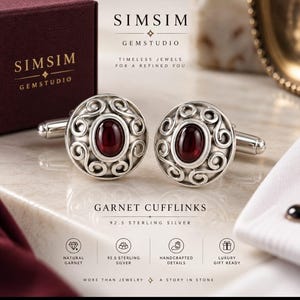 Puede incluir: Un par de gemelos redondos de plata de ley con una piedra granate roja oscura de corte ovalado central rodeada de intrincados adornos de plata. El texto SIMSIM GEMSTUDIO y GARNET CUFFLINKS 92.5 STERLING SILVER es visible.