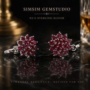 Könnte beinhalten: Ein Paar Manschettenknöpfe aus 92.5 Sterlingsilber mit einer Anordnung runder, tiefroter Edelsteine in Blütenform. Der Text SIMSIM GEMSTUDIO und 92.5 STERLING SILVER ist darüber zu sehen, mit TIMELESS ELEGANCE, REFINED FOR YOU am unteren Rand.