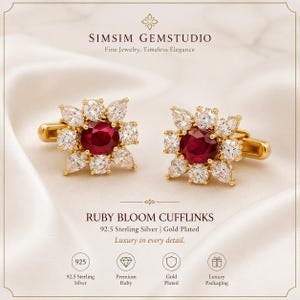 Puede incluir: Un par de gemelos de plata de ley 92.5 chapados en oro con un rubí rojo central de corte ovalado rodeado por un halo de circonitas blancas redondas y en forma de pera. El texto dice SIMSIM GEMSTUDIO y RUBY BLOOM CUFFLINKS.