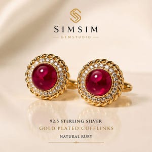 May include: A pair of gold-plated 92.5 sterling silver cufflinks featuring a central cabochon-cut natural ruby surrounded by a halo of small clear stones and a twisted rope-style border. The text SIMSIM GEMSTUDIO and 92.5 STERLING SILVER GOLD PLATED CUFFLINKS NATURAL RUBY is visible.