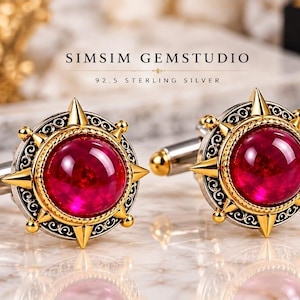 Puede incluir: Un par de gemelos de plata de ley 92.5 con una piedra roja redonda central rodeada por un marco dorado en forma de estrella con detalles de filigrana. El texto SIMSIM GEMSTUDIO 92.5 STERLING SILVER es visible sobre los objetos.