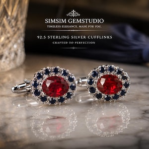 May include: A pair of 92.5 sterling silver cufflinks featuring a large oval-cut red centre stone surrounded by a halo of smaller round-cut dark blue stones. The text SIMSIM GEMSTUDIO TIMELESS ELEGANCE. MADE FOR YOU. 92.5 STERLING SILVER CUFFLINKS is visible.