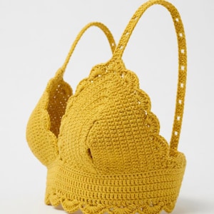 Peut inclure: Haut en crochet jaune moutarde avec bords festonnés et bretelles. Le haut fait main présente un motif de point texturé et une encolure dégagée. Les bretelles sont fixées au haut avec une série de petits trous. C'est un vêtement d'été.