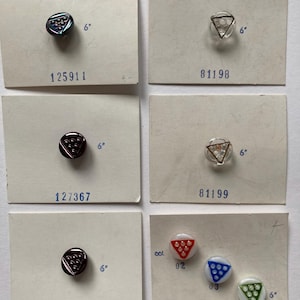 Puede incluir: Colección de botones vintage, cada uno montado en una tarjeta. Los botones presentan diseños y colores variados, incluyendo formas triangulares y redondas. Las medidas se indican como 15,24 cm.