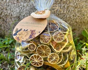 May include: A clear plastic bag filled with dried orange and lime slices. The bag is tied with twine and has a brown paper tag with the text "LULUBEL NATURALS" and a floral design.