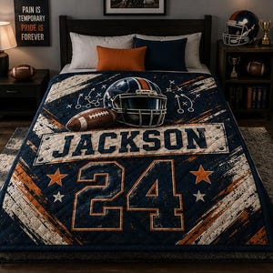Op de afbeelding: Een doorgestikte sprei in marineblauw, oranje en wit met een footballhelm, een football en spelschema's. Het ontwerp bevat de naam JACKSON in grote blokletters boven het nummer 24, geaccentueerd door sterren op een verweerde achtergrond.