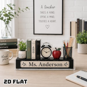 Puede incluir: Un organizador de escritorio rectangular negro con una parte superior de acrílico transparente que presenta una placa con el nombre impreso Ms. Anderson. Contiene una pequeña planta en maceta, tres libros en miniatura, un despertador analógico negro, una manzana roja y un portalápices de malla.