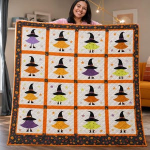 May include: A quilted throw blanket featuring a grid of sixteen squares, each displaying a witch character wearing a black hat and a colorful dress. The squares are separated by orange sashing and framed by a dark border with autumn leaf patterns.