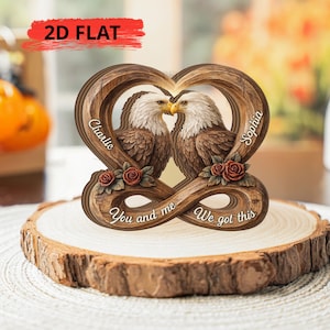 Peut inclure: Ornement en bois en forme de cœur avec deux aigles qui s'embrassent, avec les noms "Charlie" et "Sophia" inscrits. L'ornement comprend le texte "You and me" et "We got this", et est décoré de roses.