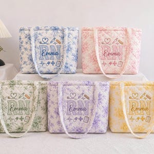 May include: Five quilted tote bags in blue, pink, green, purple, and yellow floral patterns. Each bag features embroidered medical icons, a heart-shaped stethoscope, and the text "RN" with the name "Emma" stitched in the center of the design.