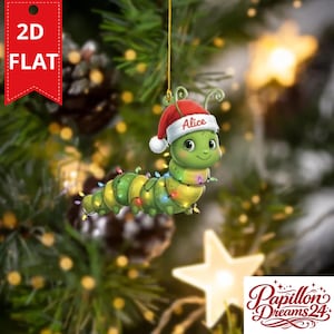 Puede incluir: Un adorno plano y bidimensional para árbol de Navidad con forma de oruga verde que lleva un gorro de Papá Noel rojo y blanco con el nombre Alice impreso en el borde. La oruga está envuelta en una cadena de luces navideñas brillantes.