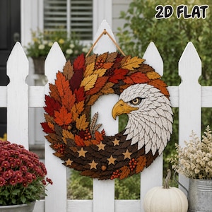 May include: A circular wreath featuring a bald eagle head on the right side, with the left side composed of layered autumn leaves in shades of red, orange, and brown. The design includes small wooden stars, berries, and wheat stalks. Text reads 2D FLAT.