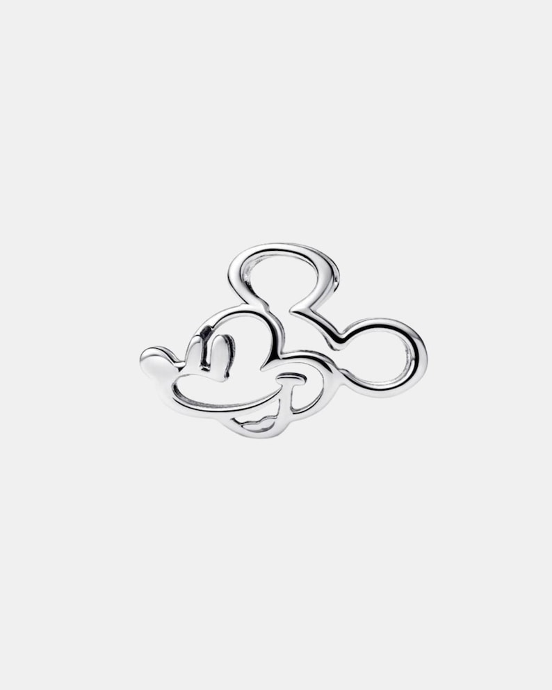 May include: A silver charm depicting Mickey Mouse's head and ears. The charm is a solid outline with a smooth, reflective surface. The design is a classic representation of the iconic Disney character.