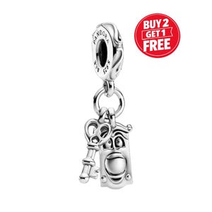 May include: A silver charm featuring a key and a door knocker design. The charm is suspended from a larger silver bead with the brand name "Pandora" engraved on it. The charm is made of silver and has intricate details.