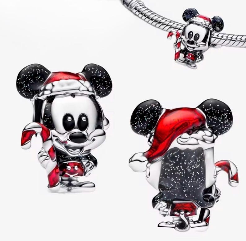 May include: Silver Mickey Mouse charm with black ears and a red Santa hat. The charm is holding a red and white candy cane. One charm is attached to a silver bracelet. Festive holiday jewellery.