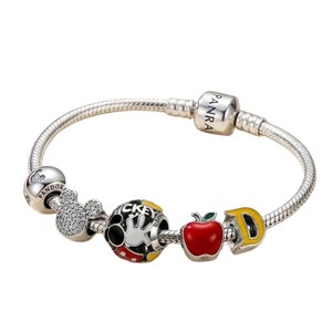 Puede incluir: Una pulsera de plata con varios abalorios tem&aacute;ticos de Disney. Los abalorios incluyen una cabeza de Mickey Mouse, un guante de Mickey Mouse, una manzana roja y la letra "D" amarilla. La pulsera tiene un dise&ntilde;o de cadena de serpiente.
