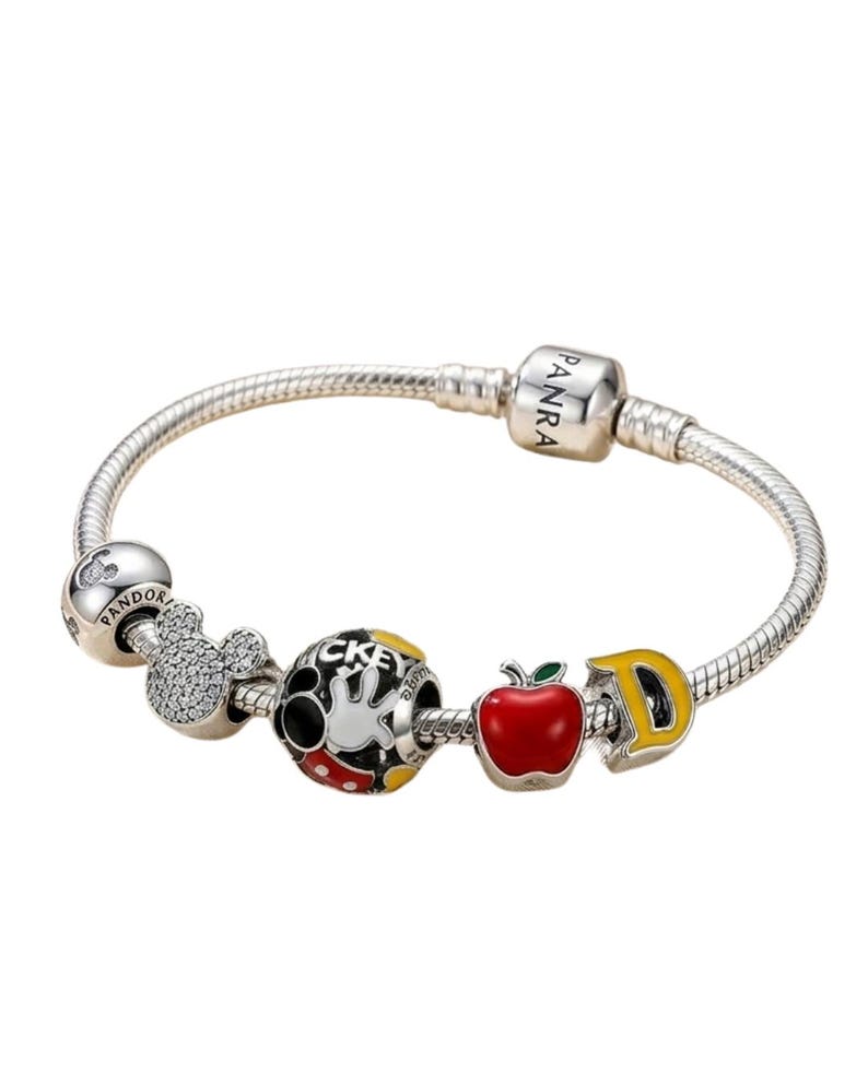 Puede incluir: Una pulsera de plata con varios abalorios tem&aacute;ticos de Disney. Los abalorios incluyen una cabeza de Mickey Mouse, un guante de Mickey Mouse, una manzana roja y la letra "D" amarilla. La pulsera tiene un dise&ntilde;o de cadena de serpiente.