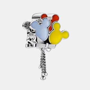 May include: A silver charm with three Mickey Mouse head shapes in red, blue, and yellow enamel. The charm has a dangling chain with small silver beads. The word "PANDORA" is visible on the top.