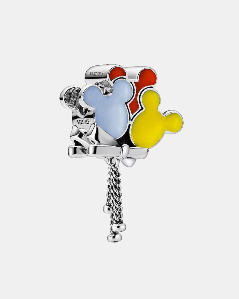 May include: A silver charm with three Mickey Mouse head shapes in red, blue, and yellow enamel. The charm has a dangling chain with small silver beads. The word "PANDORA" is visible on the top.