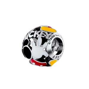 Puede incluir: Un charm plateado con fondo negro y la palabra "MICKEY" en blanco. El charm presenta una mano blanca con detalles rojos y amarillos, y tambi&eacute;n se ve la palabra "DISNEY".