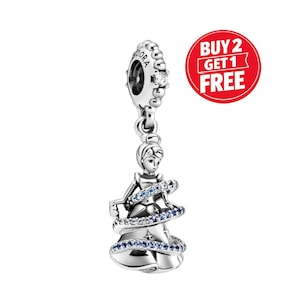 May include: A silver charm featuring a princess in a gown, with blue and clear accents. The charm has a loop at the top with the word "PANDORA" and a small gem. A red circle with the text "BUY 2 GET 1 FREE" is in the background.