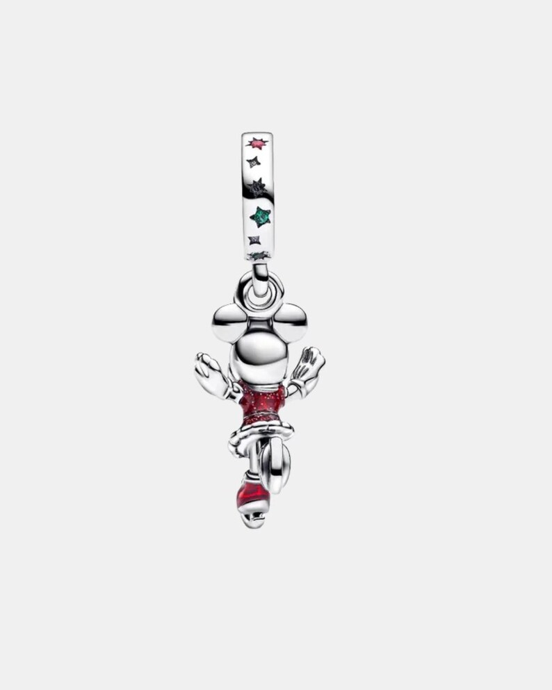 May include: A silver charm featuring a character with round ears, wearing a red glittery dress and red skates. The bail is decorated with small, colorful star-shaped accents in red, black, and green, adding a subtle touch of color to the metallic finish.