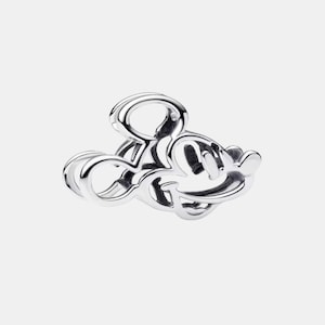 May include: A silver charm in the shape of Mickey Mouse's head. The charm is made of a shiny, reflective metal and features the iconic mouse's silhouette with its large ears and smiling face. The charm is a collectible item.
