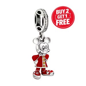 Pu&ograve; includere: Un charm color argento raffigurante un personaggio dalle grandi orecchie che indossa un cappotto rosso con dettagli gialli e scarpe rosse. L'anello superiore &egrave; incastonato con piccole pietre chiare. Un cerchio rosso riporta BUY 2 GET 1 FREE.