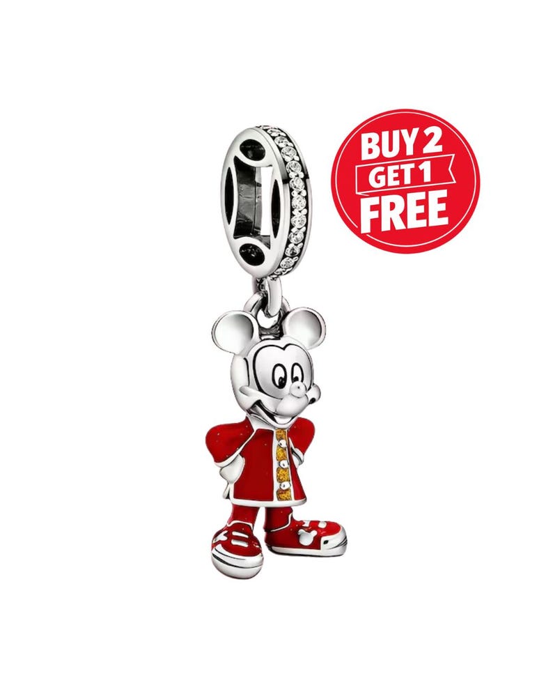 Pu&ograve; includere: Un charm color argento raffigurante un personaggio dalle grandi orecchie che indossa un cappotto rosso con dettagli gialli e scarpe rosse. L'anello superiore &egrave; incastonato con piccole pietre chiare. Un cerchio rosso riporta BUY 2 GET 1 FREE.