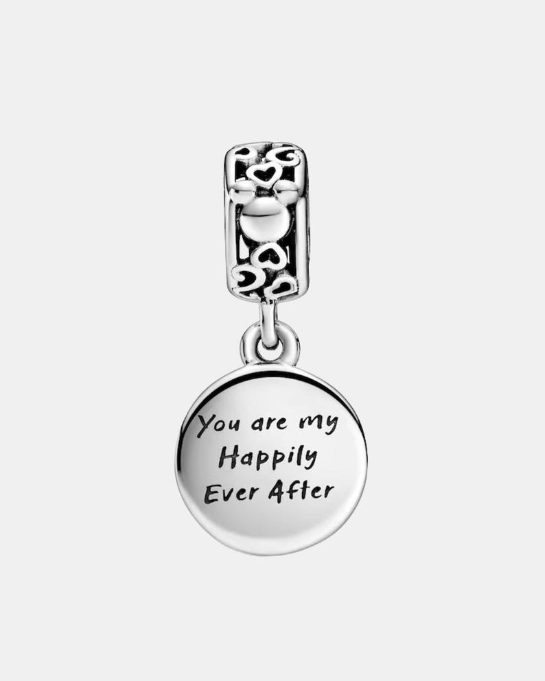 May include: A silver charm with a heart-shaped design and the words "You are my Happily Ever After" engraved on a round pendant. The charm has a decorative top with heart cutouts.