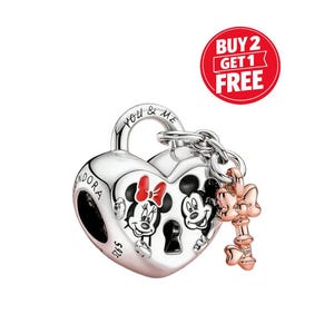 May include: A silver heart-shaped charm featuring Mickey and Minnie Mouse. The charm has a key attached and the words "You & Me" are engraved on the top. This Disney-themed charm is a piece of jewellery.