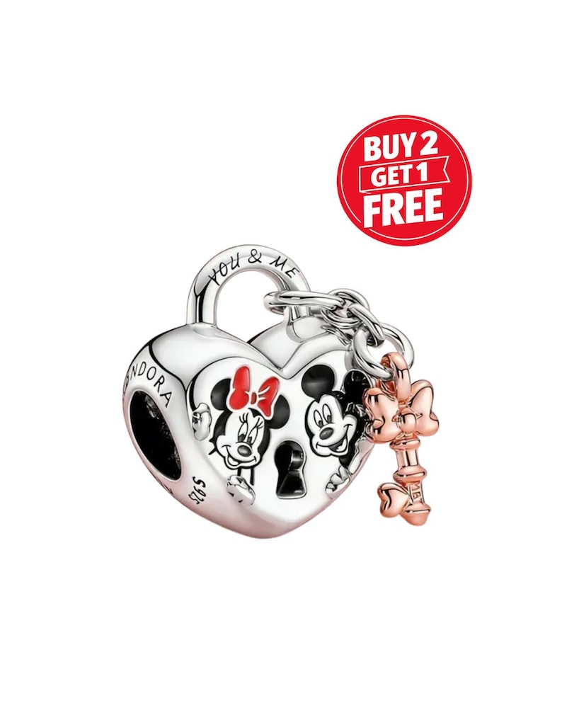 May include: A silver heart-shaped charm featuring Mickey and Minnie Mouse. The charm has a key attached and the words "You & Me" are engraved on the top. This Disney-themed charm is a piece of jewellery.