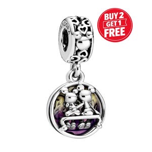 May include: A silver charm with a round pendant featuring two figures seated on a bench, set against a purple and yellow background. The charm has a heart-shaped design and the word "Pandora" is visible.