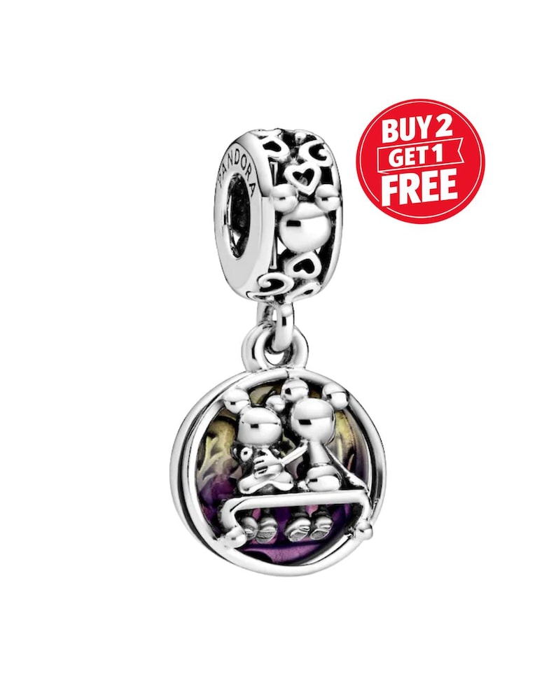 May include: A silver charm with a round pendant featuring two figures seated on a bench, set against a purple and yellow background. The charm has a heart-shaped design and the word "Pandora" is visible.