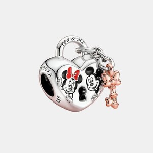 May include: A silver heart-shaped charm featuring Mickey and Minnie Mouse. The charm has a key and bow attached. The words "YOU & ME" are engraved on the top. This is a Disney-themed jewellery item.