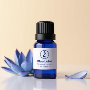 以下が含まれることがあります： 黒いキャップと「Blue Lotus」と書かれた白いラベルが付いた、コバルトブルーのエッセンシャルオイルボトル。青い蓮の花と花びらがボトルの隣にあります。ボトルには5 mlのオイルが入っています。