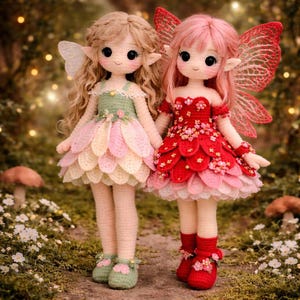 May include: Two handmade crochet fairy dolls. One doll wears a green and pastel petal dress, the other a red petal dress. Both dolls have wings, pointed ears, and are holding hands. The dolls are standing in a garden setting.