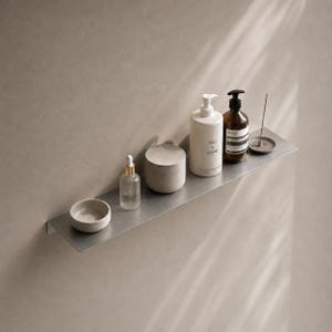Op de afbeelding: Een minimalistisch metalen plankje met diverse badkamer- en huidverzorgingsproducten. Items zijn onder meer een kleine kom, een glazen fles met een druppelaar, een cilindrische container, een witte fles met een pomp, een bruine fles en een kleine wierookhouder.