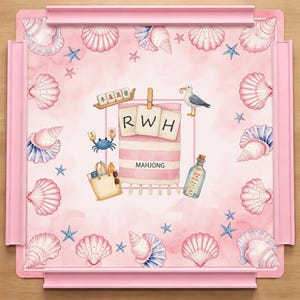 May include: A square pink mahjong mat featuring a border of watercolor seashells and starfish. The center displays a beach towel with the letters RWH, a tote bag, a seagull, a crab, a message in a bottle, and mahjong tiles with Chinese characters.