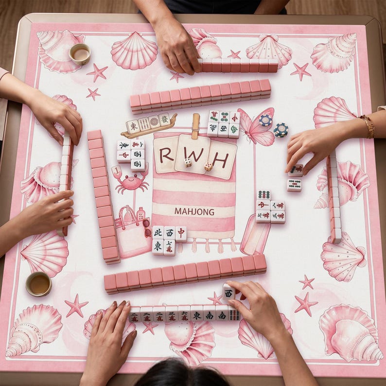 May include: A square mahjong mat featuring a pink and white beach-themed pattern with seashells, starfish, and a central graphic of a towel with the letters RWH and the word MAHJONG. The mat is covered with rows of pink mahjong tiles and game pieces.