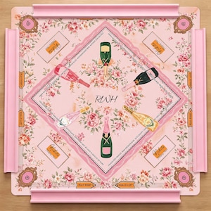 May include: A square board game with a light pink floral background featuring four champagne bottles in green, pink, and gold. The center displays the letters RWH. Four corners contain ornate frames, and the edges feature pink racks and text.